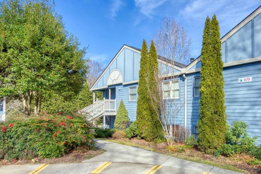 a blue house with trees in front of a driveway at Beehive Condo in Lake Junaluska