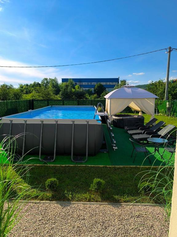 a swimming pool with an umbrella and chairs and a table at Holiday Home Norr in Bihać
