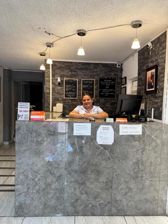 a woman sitting at a counter in an office at Hotel Posada Jardín Aguascalientes in Aguascalientes