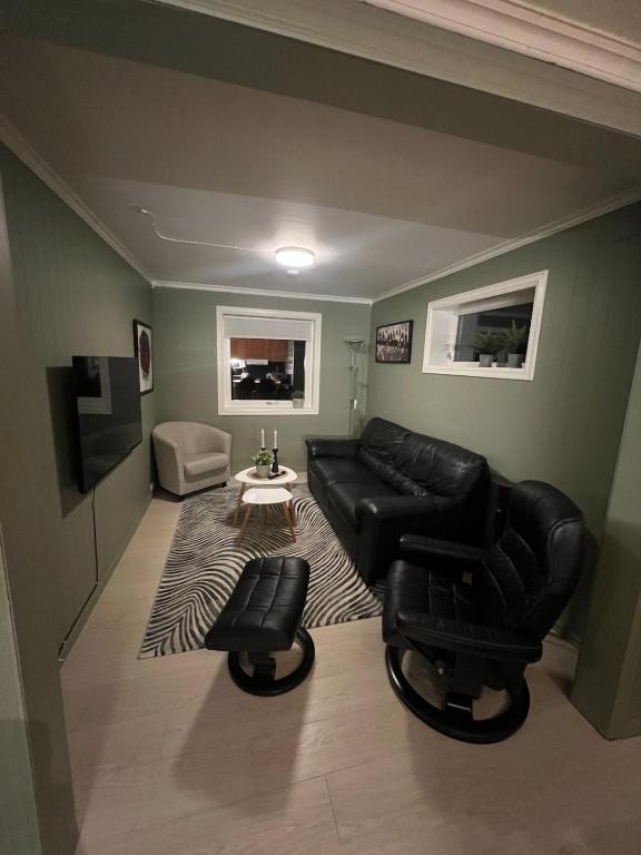 a living room with a black leather couch and chairs at Basement apartment on Ulstein in Ulstein