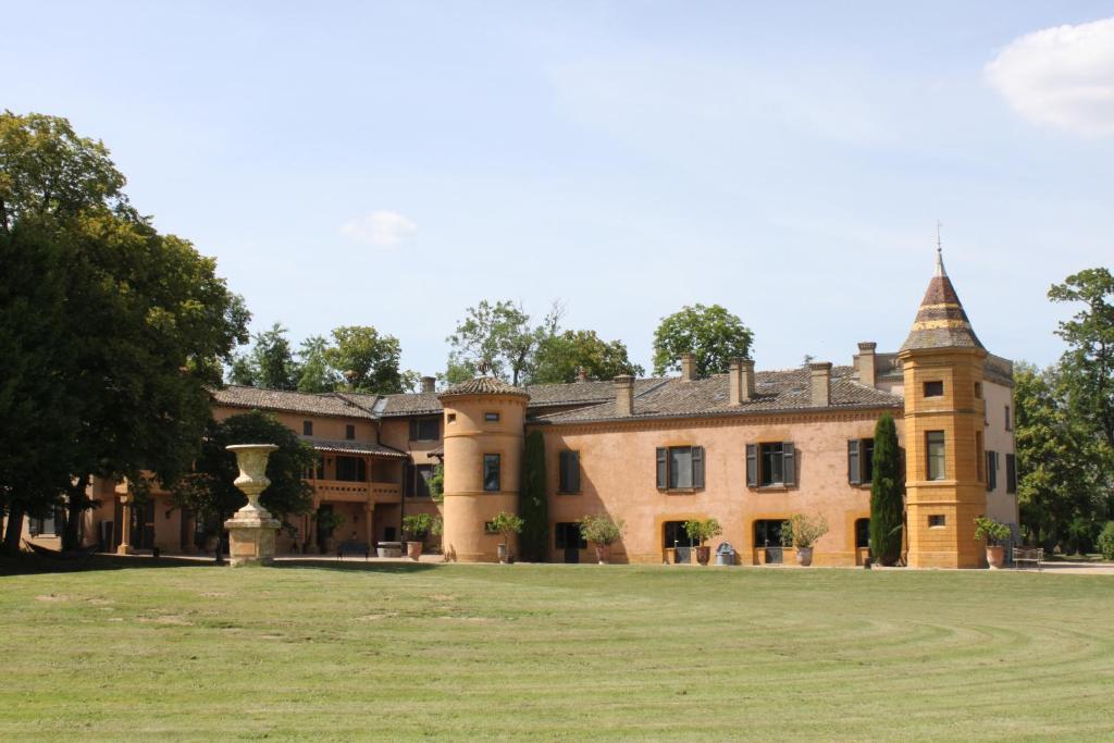 un grand bâtiment avec une pelouse devant lui dans l'établissement Château de Briante, à Saint-Lager