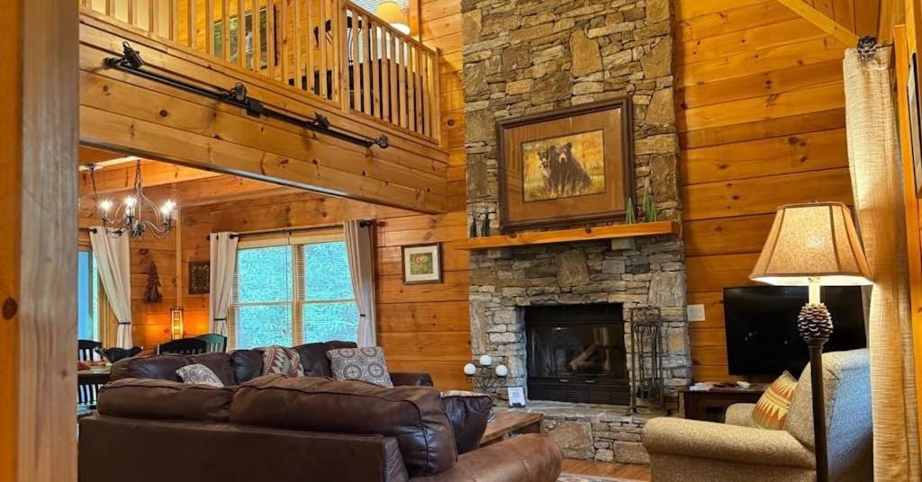 a living room with couches and a stone fireplace at Hickory Creek Hideaway in Maggie Valley