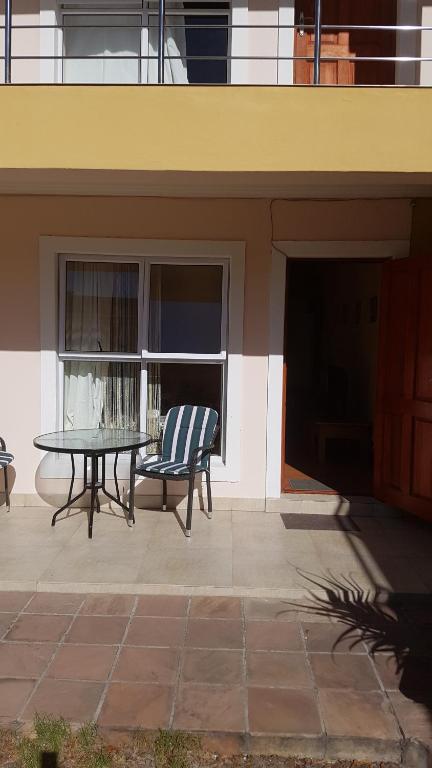 a patio with a table and a chair next to a building at Natalie Guesthouse in Bloubergstrand