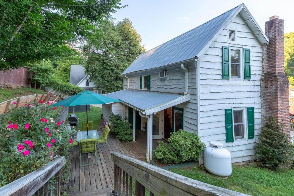 a white house with an umbrella and a wooden deck at The Reed House in Dillsboro