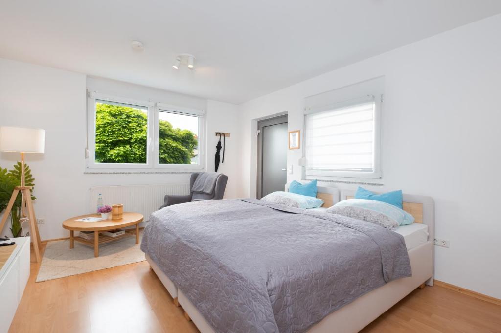 a bedroom with a bed and a table and two windows at Modernes Apartment mit Küche, Parkplatz, WLAN - Nähe Schwäbisch Gmünd in Waldstetten