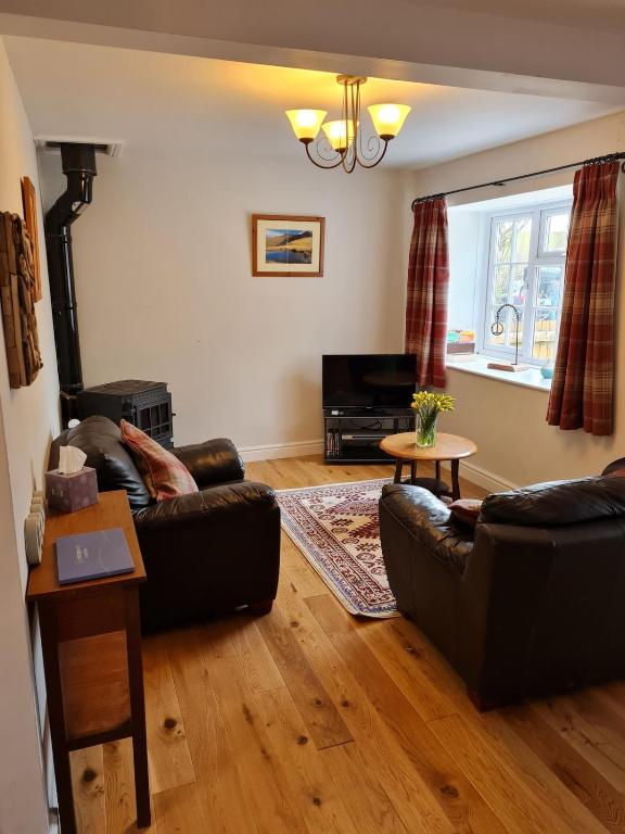 a living room with two leather couches and a fireplace at Bwthyn canol in Sennybridge