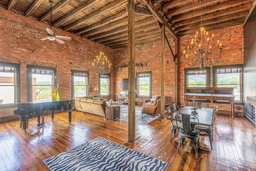 a living room with a brick wall and a piano at Brick Loft Penthouse on Main in Brevard