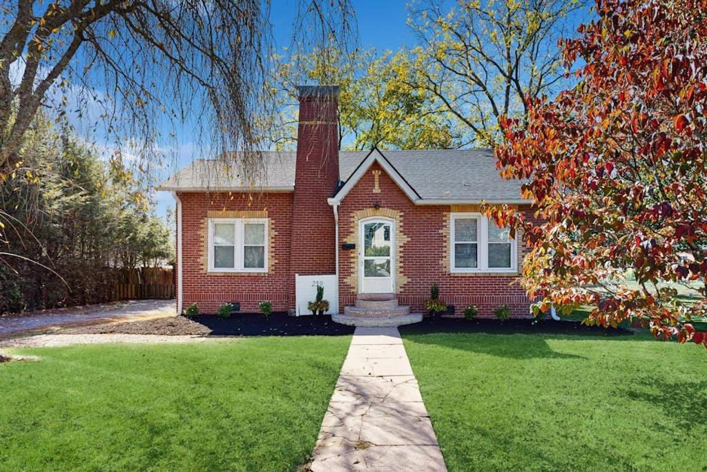 a red brick house with a chimney on a lawn at Main Street Brick Cottage in Brevard