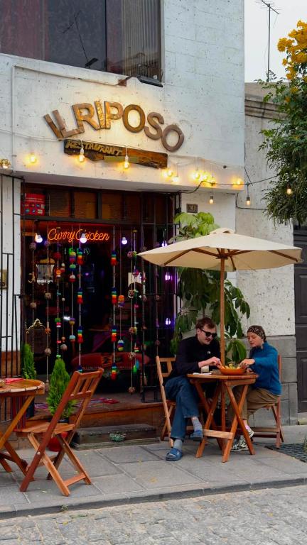 two people sitting at a table under an umbrella at Il Riposo in Arequipa