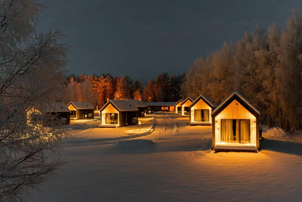 a group of lodges in the snow at night at Nilimella Camping & Resort in Sodankylä