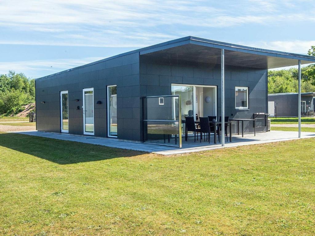 a black building with a table and chairs in a field at 4 star holiday home in Ringkøbing in Ringkøbing