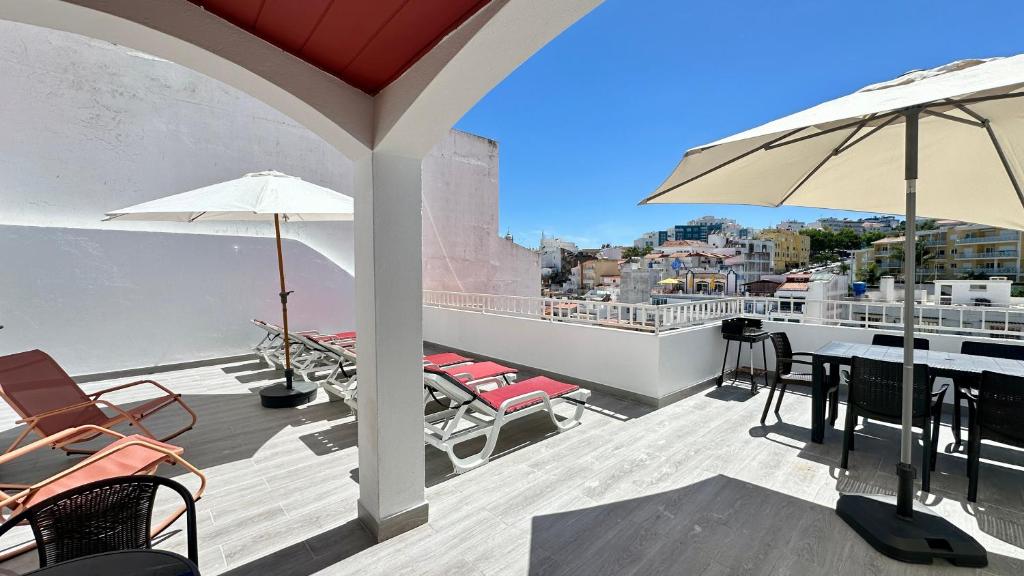 a balcony with chairs and tables and an umbrella at Liberdade - Near the beach - 6 Pax - Albufeira in Albufeira