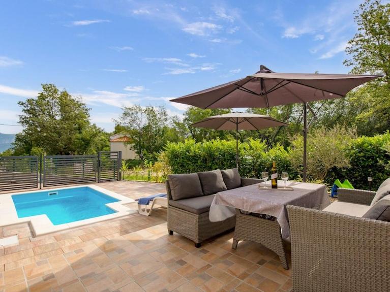 a patio with a table and an umbrella and a pool at Kuca za odmor Vila Agnes in Županje