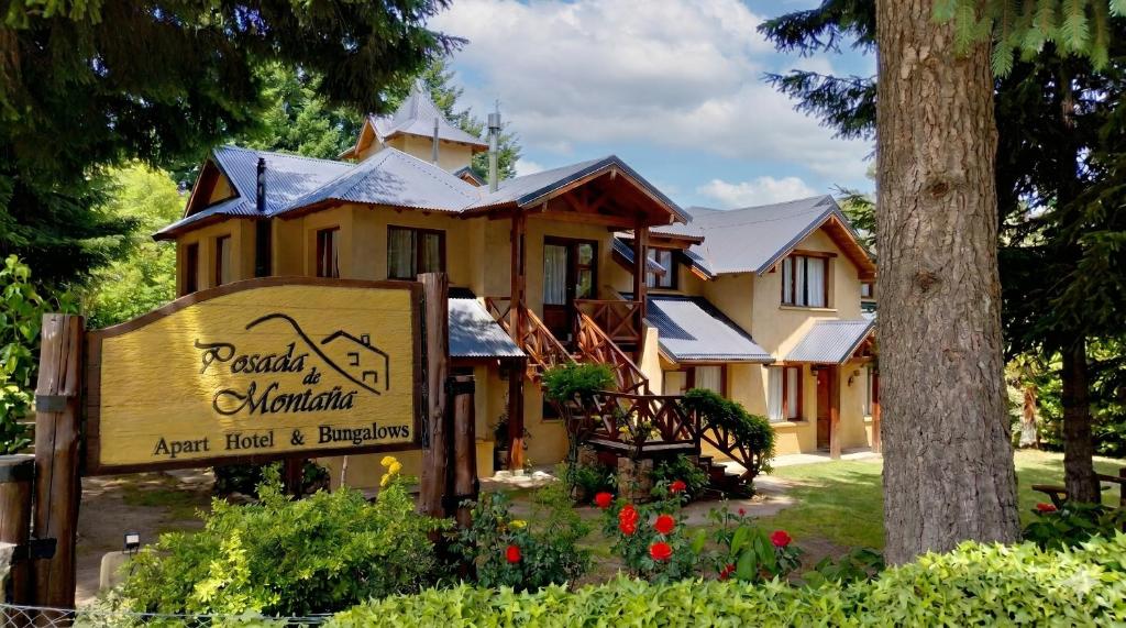 a large yellow house with a sign in front of it at Posada de Montaña - Apart Hotel in San Carlos de Bariloche