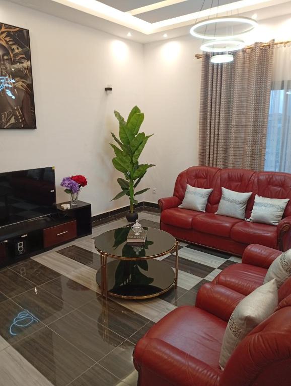a living room with red couches and a tv at Résidence Prestige KGV Appt 302 in Douala