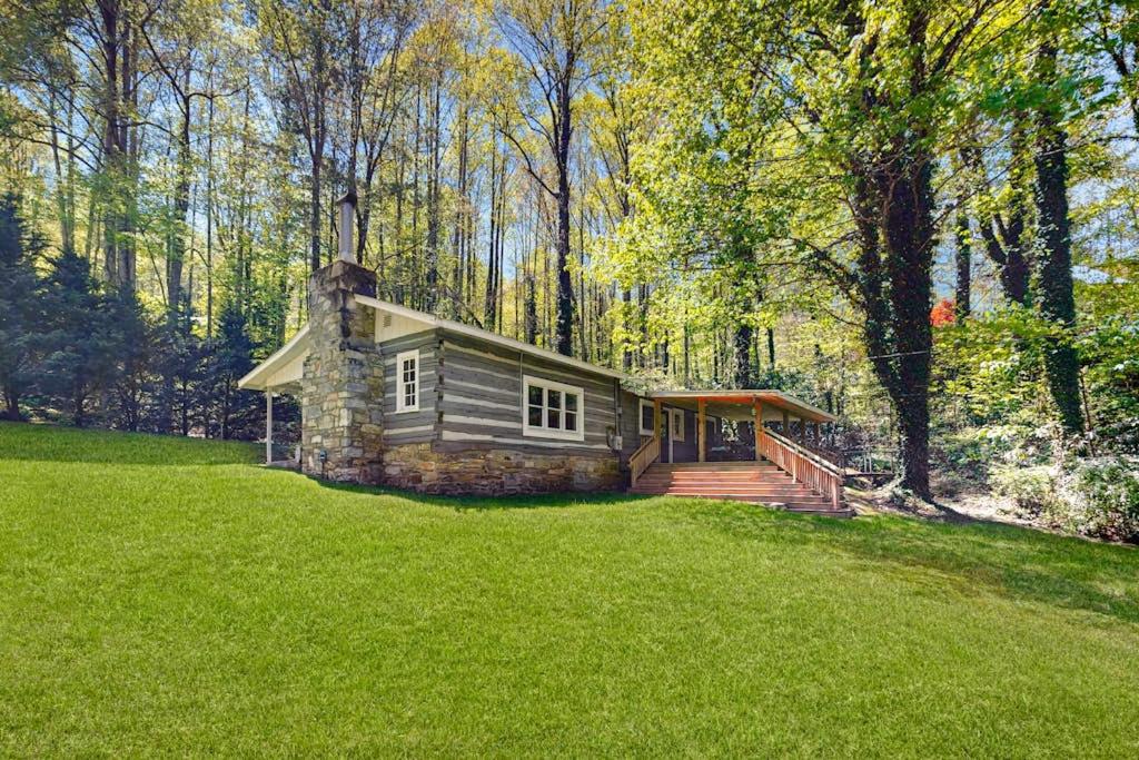 a log cabin in the middle of a green field at Bradley Bear Hideaway in Maggie Valley
