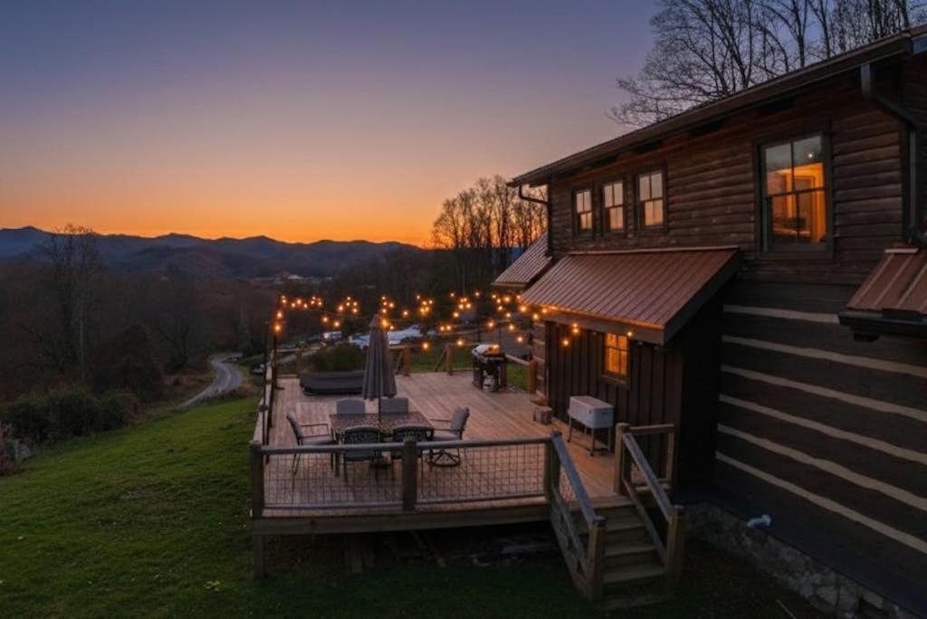a deck on the side of a house at sunset at Moss Creek Cabin in Sylva