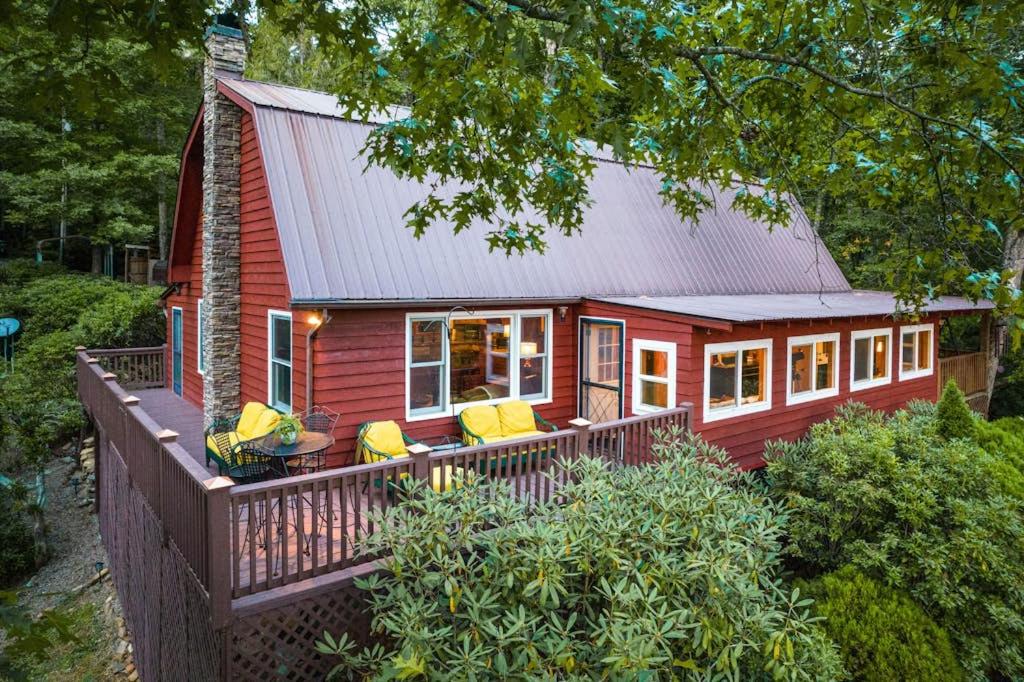 a red tiny house with yellow chairs on a deck at The Treehouse in Franklin