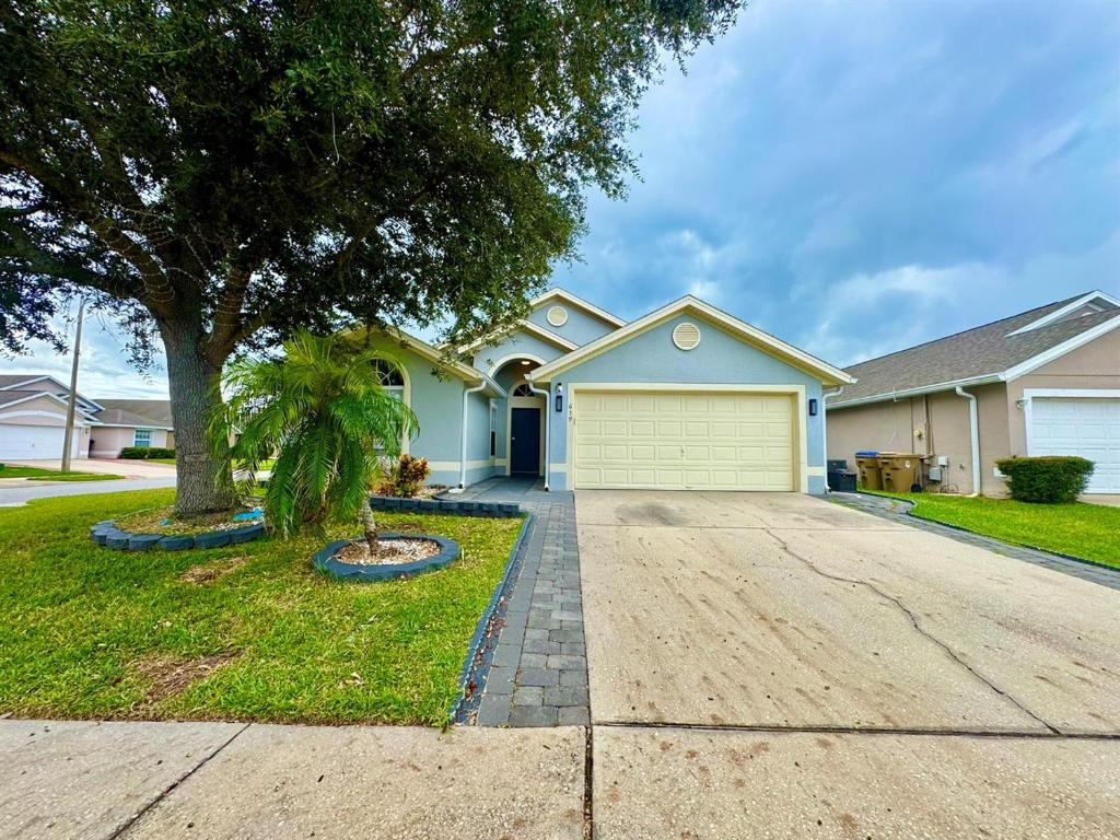 a house with a tree and a driveway at Modern 4BR2BA with pool in gated community in Kissimmee