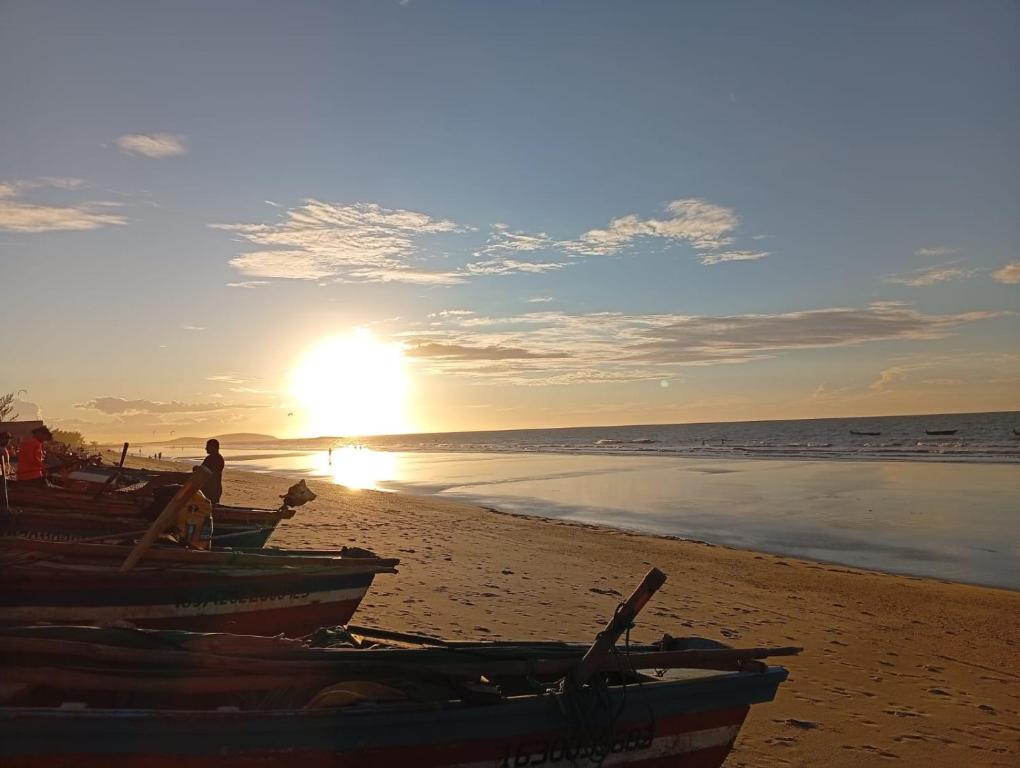 a person sitting on a beach with boats on the sand at Casa Aura Solis Preá in Prea