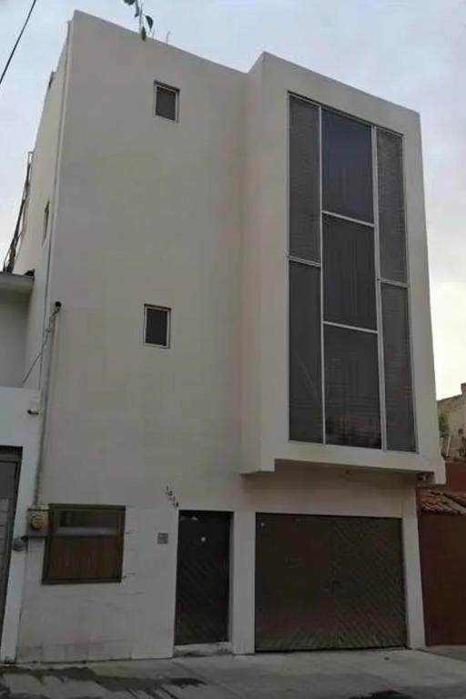 a white building with three windows and two garage at Hotel 7 Rooms in Guadalajara