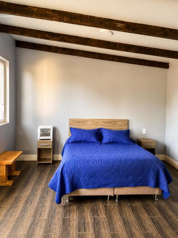 a bedroom with a bed with a blue comforter at Cabaña bosquepaz in Algarrobo