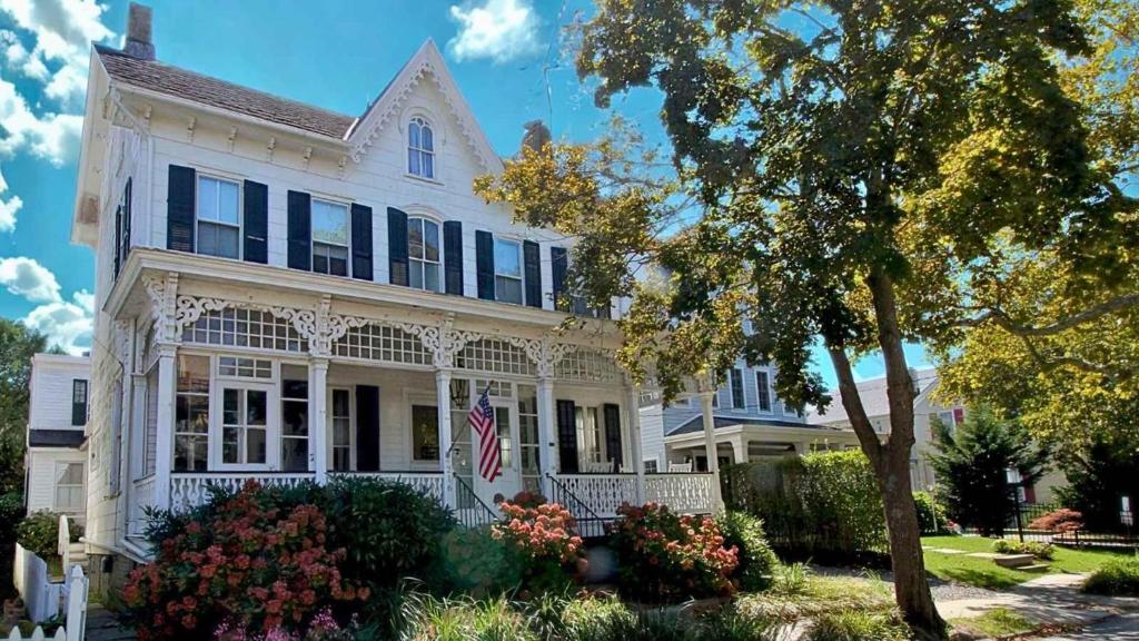 a white house with a flag in the front yard at Victorian On North in Cape May