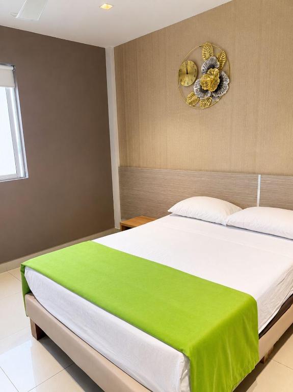 a bedroom with a large bed with a green blanket at Hotel Condina Pereira in Pereira