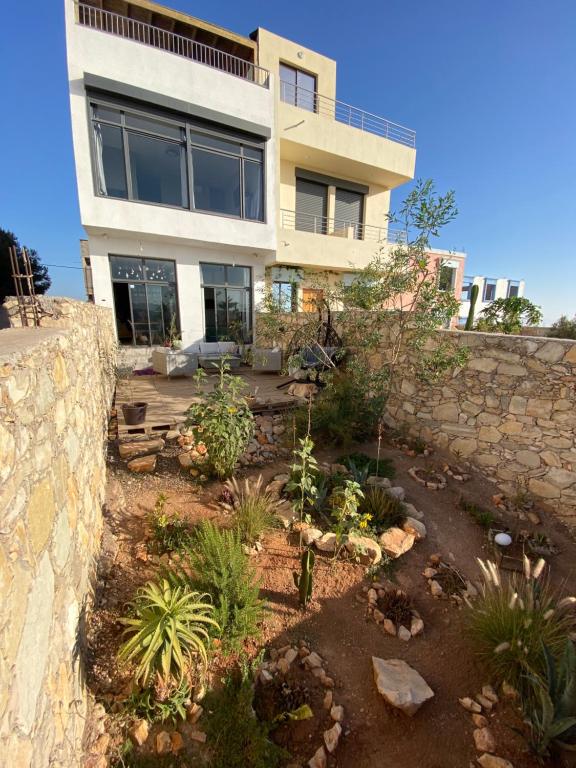 a house with a stone wall and a garden at Villa Tafoukt Taghazout in Taghazout