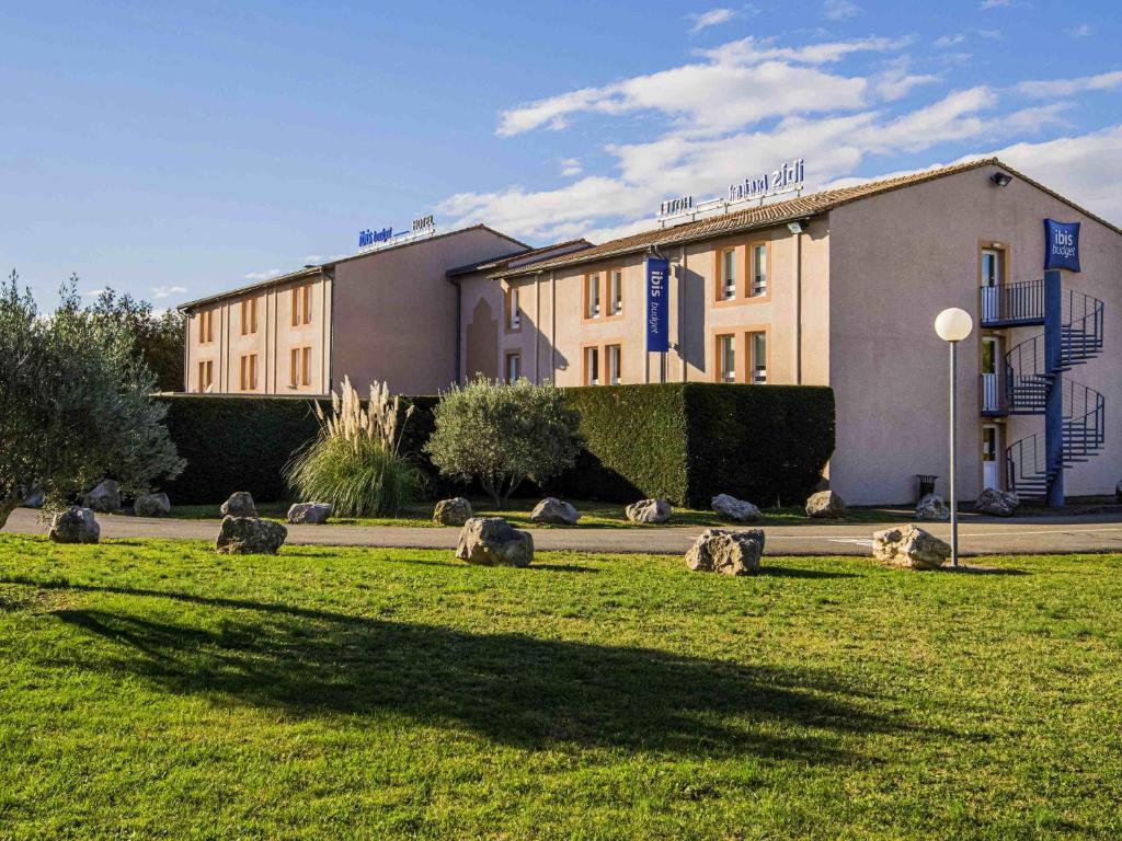 a group of animals in the grass in front of a building at Ibis Budget Bollene in Bollène