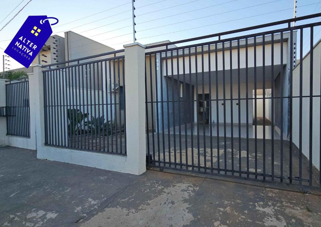 a gate in front of a building with a house at Casa Indaiá in Primavera do Leste