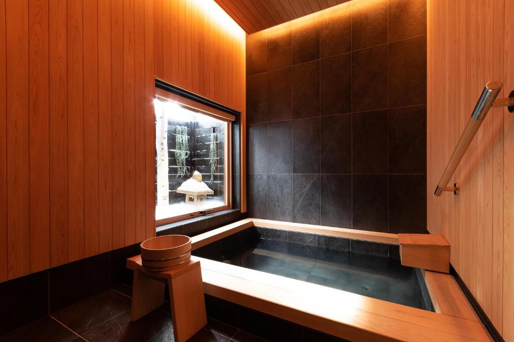 a bathroom with a tub with a window at Furano Lofts & Chalet in Furano