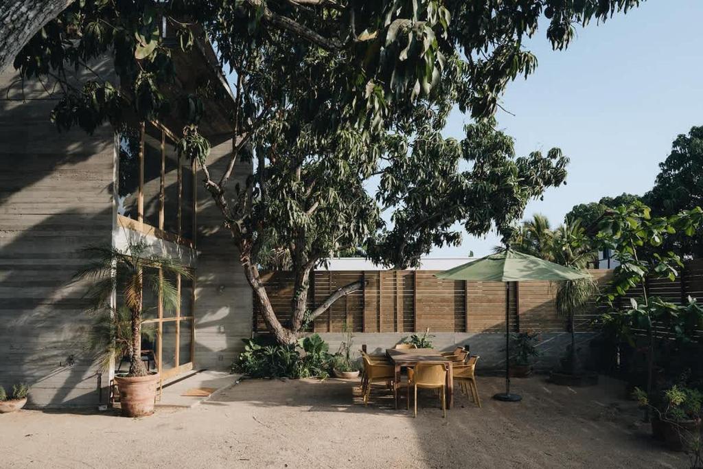 a patio with a table and an umbrella at CASA NU La Saladita surf point in Temalhuacán