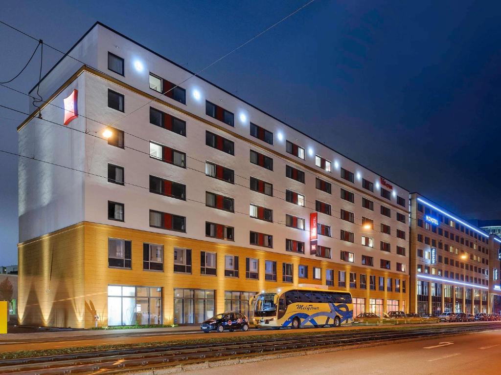 a large building with a bus parked in front of it at Ibis München City Arnulfpark in Munich