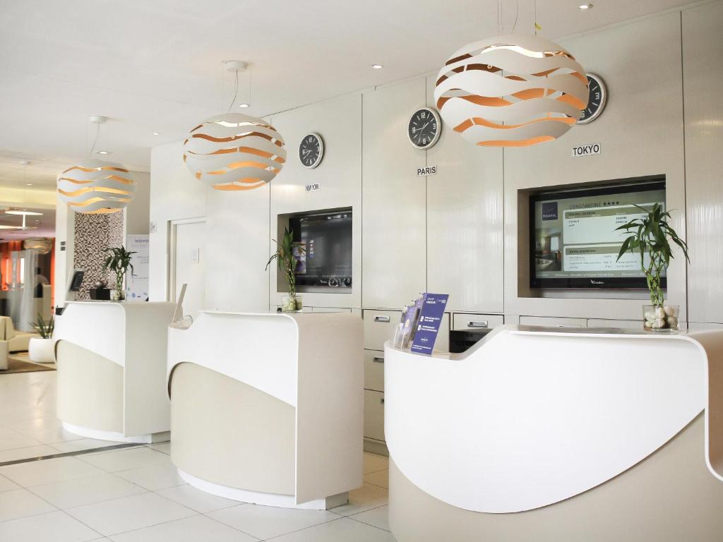 a lobby with white counters and pendant lights at Novotel Constantine in Constantine