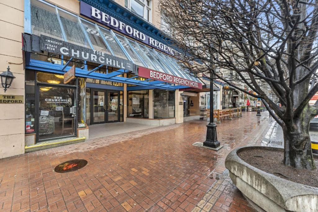 a street with shops and a tree on a sidewalk at Bedford Regency Hotel, Trademark Collection by Wyndham in Victoria