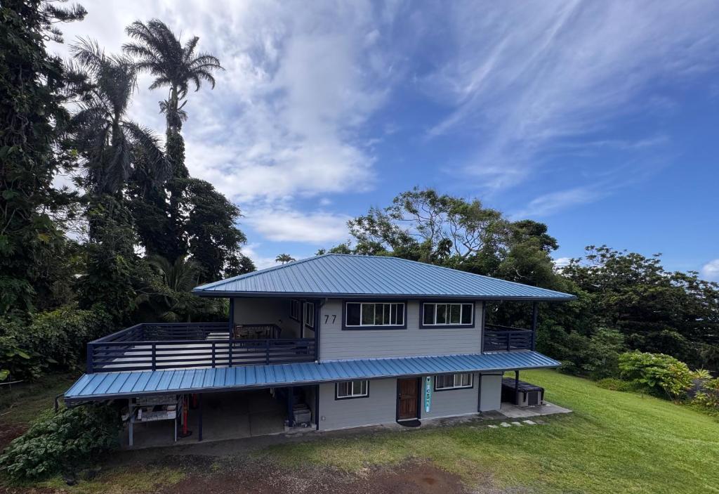 a house with a blue roof and a palm tree at Hana Homestead in Hana