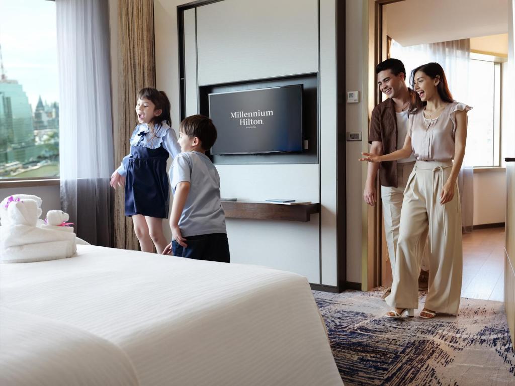 A bright guest room has a large bed, city-facing window and separate sitting area.