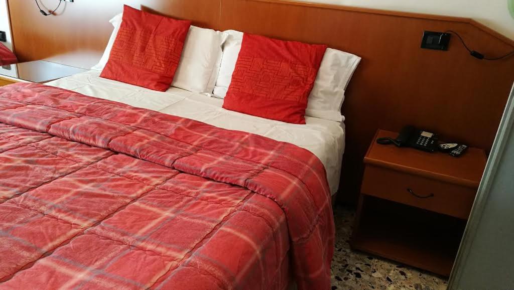 a bedroom with a bed with red and white pillows at Ristorante Albergo Roma in Legnano