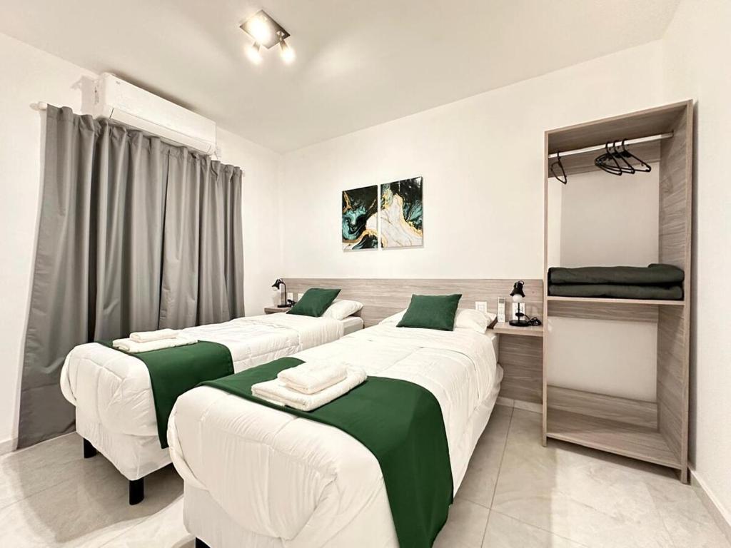 two beds in a room with green and white at Vela Villa Apart N3 in Villa Ángela