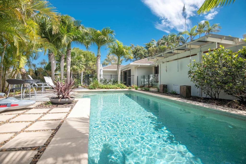 a swimming pool in front of a house with palm trees at Noosa Sunrise - Pet-friendly with Pool in Sunrise Beach