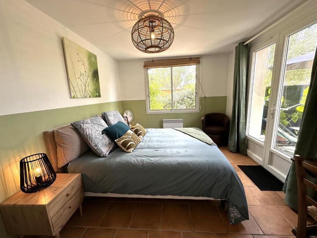 a bedroom with a bed and a lamp and windows at Vent d'ouest in Messanges