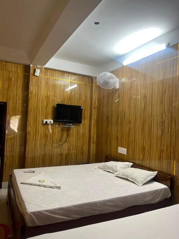 a bedroom with a bed and a tv on a wooden wall at Panthanibas momochitte in Bakkhali