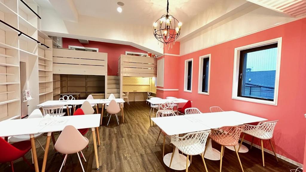 a restaurant with white tables and pink walls at Cafe&Hostel Kimi to Ichigo in Osaka