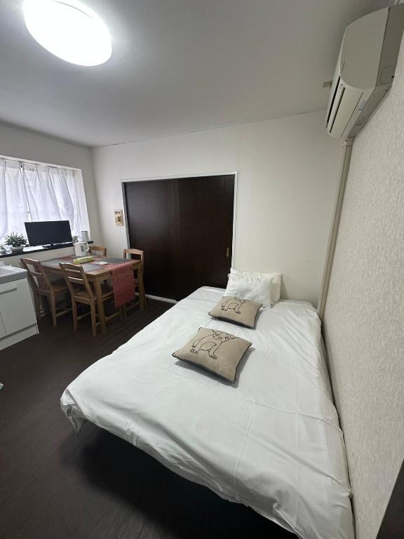 a bedroom with a large white bed with a desk at Panda Home Umeda 01 in Osaka