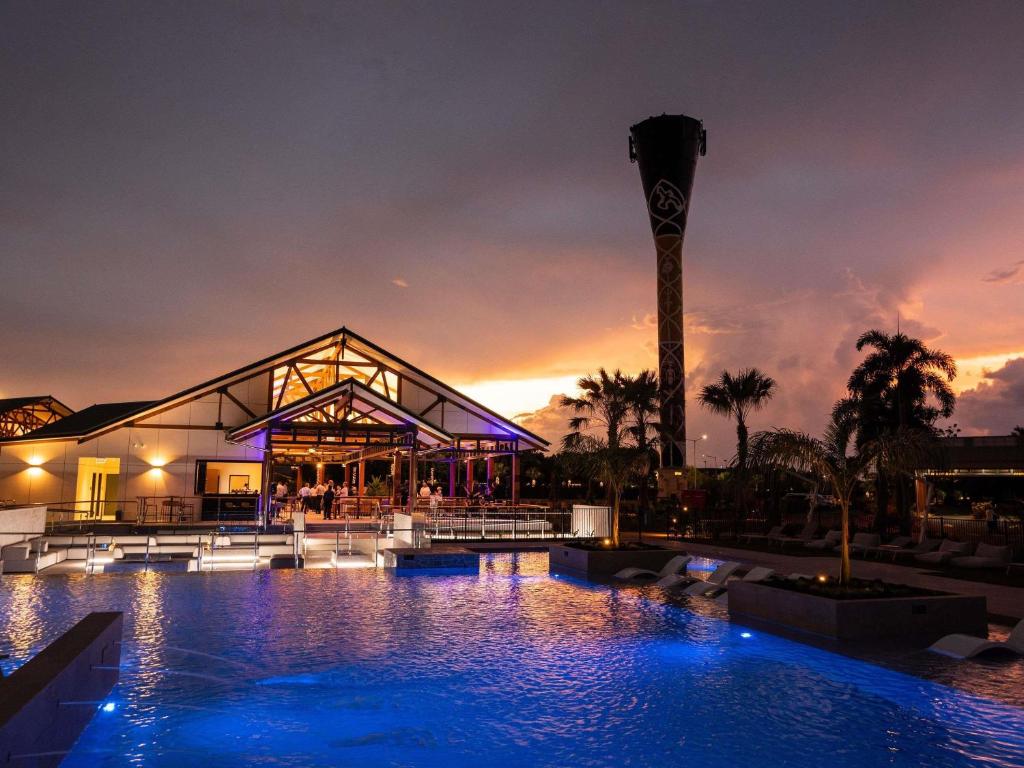 a building with a swimming pool at night at Mercure Darwin Airport Resort in Darwin