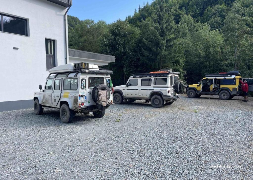 two jeepneys parked in a gravel lot next to a building at Camping Colibita in Colibiţa