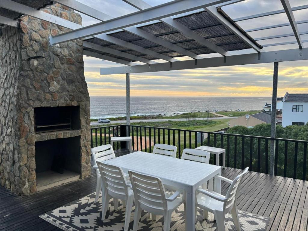 a white table and chairs on a deck with a fireplace at Seaview Sunsets in Gqeberha