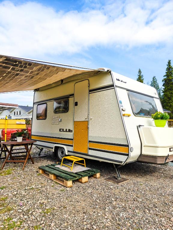 a white and yellow caravan parked next to a picnic table at Camper Somá in Muonio
