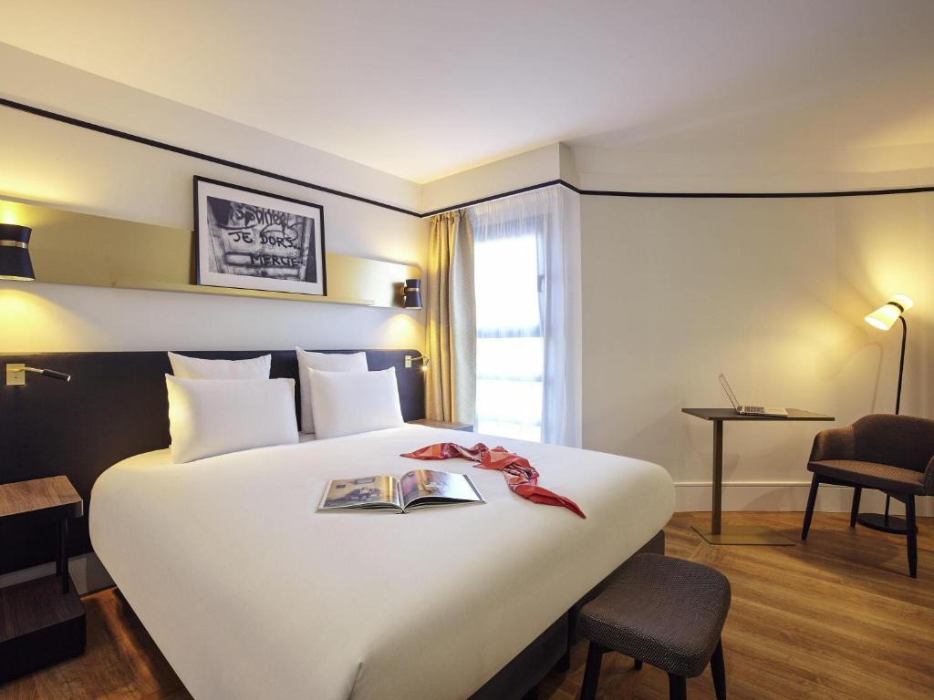 a hotel room with a large bed with a book on it at Mercure Paris Saint-Ouen in Saint-Ouen